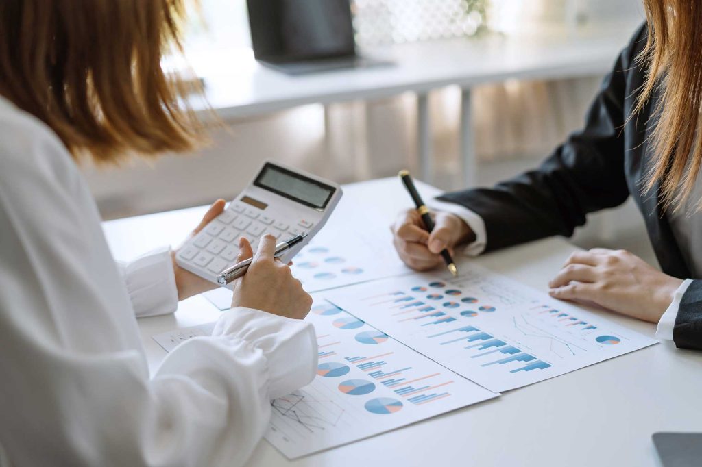 group of business people brainstorm meeting with graphs and calculator